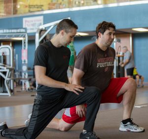 photo of trainer helping member doing kneeling squats
