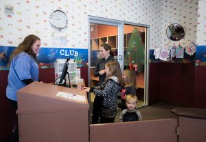 photo of a mom and three kids checking into the kids club