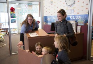 photo of a mom and three kids checking into the kids club
