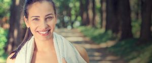Photo of young athletic woman smiling in the park after runing