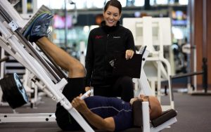 trainer watching over a man doing leg presses