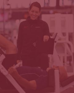 photo of female trainer watching over a man do leg presses - with red overlay