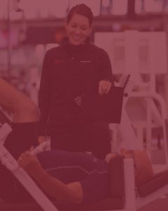 photo of female trainer watching over a man do leg presses - with red overlay