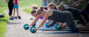 photo of an outdoor group class using a wheel for pushups
